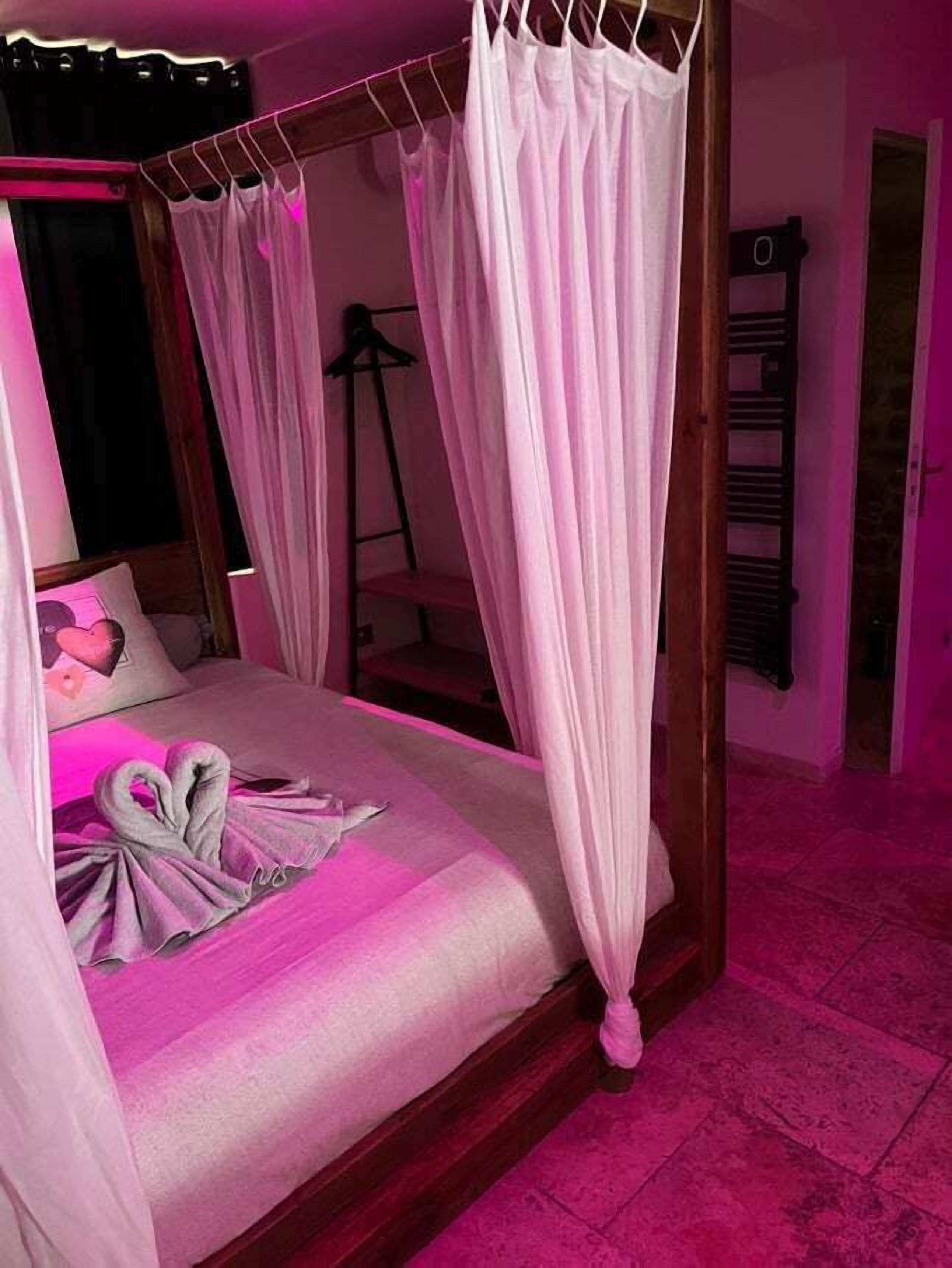 A bedroom with a canopy bed, a ladder, and a bed with a towel arrangement.