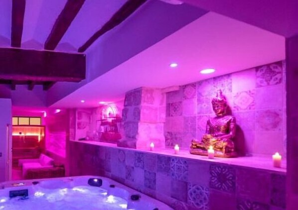 Une pièce dotée d’une grande statue, d’un jacuzzi et d’un mur recouvert de carreaux décoratifs.