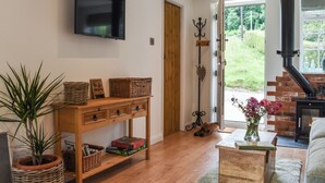 Una sala de estar con una mesa de madera, un televisor montado en la pared, una chimenea y vistas al exterior.