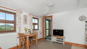 Una habitación acogedora con una mesa de comedor de madera, sillas, un televisor y vistas al exterior.