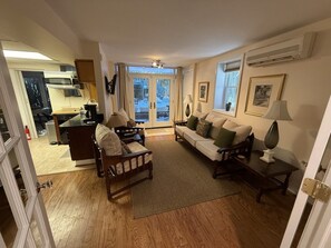 Sala de estar con sofá, sillón y mesa de centro, zona de cocina con estufa y microondas, y mesa de comedor con sillas.