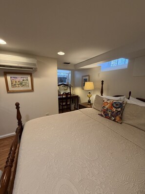 Un dormitorio con cama, escritorio, silla, lámpara y ventana.