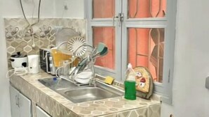 A compact kitchen with a sink, stove, and window. - Cosy studio at la riviera palmeraie (Abidjan)