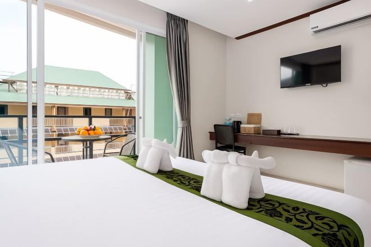 Une chambre d’hôtel équipée d’un lit, d’un bureau, d’une télévision et d’un balcon avec une table et des chaises.