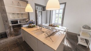A modern kitchen with a central island, white cabinetry, and pendant lighting.