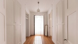 A hallway with white doors, wooden flooring, and a hanging light fixture.
