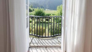 A room with a balcony overlooking a mountainous landscape.