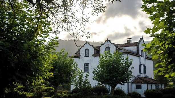 A white building with multiple windows and a garden in front.