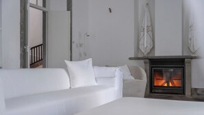 A modern living room with a white sofa set, a fireplace, and a view of a balcony.