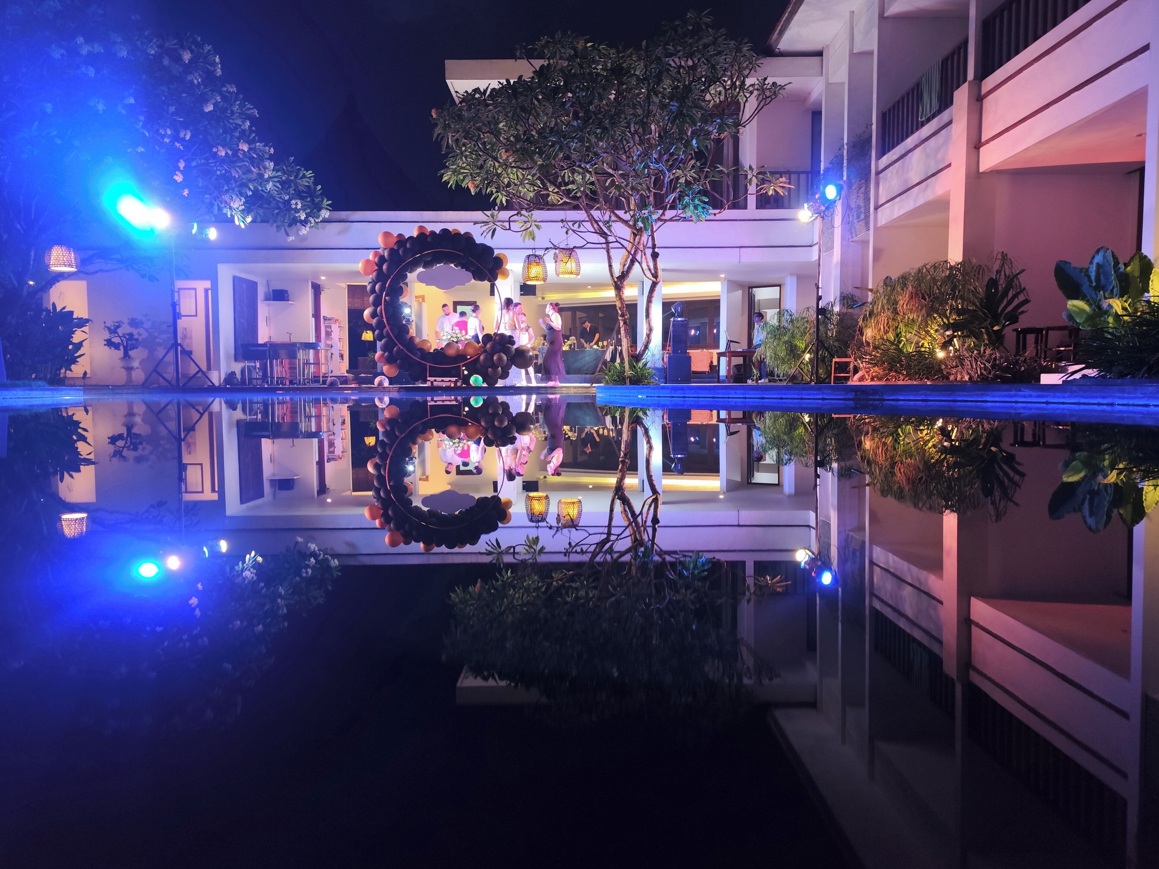 A hotel courtyard with a reflective pool, a decorative wreath, and indoor lighting.