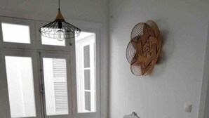 A room with two white chairs, a small table, and a hanging light fixture. - GuestReady - Cheerful Ponta Delgada townhouse (Ponta Delgada)