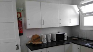 A kitchen with white cabinets, a black countertop, and a window. - GuestReady - Cheerful Ponta Delgada townhouse (Ponta Delgada)