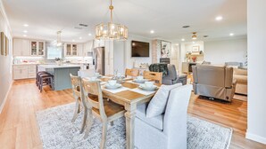 A spacious kitchen with a central island, wooden dining table, and modern lighting fixtures. - Patio, Yard, Views: Modern Home in Longview (Longview)