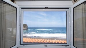 A window with a view of the ocean and a rocky cliff.