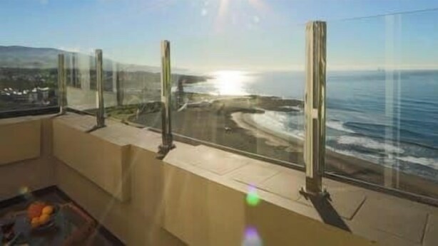 A balcony with a view of the ocean and a distant cityscape. - GuestReady - Stunning TopFloor OceanView (Ponta Delgada)