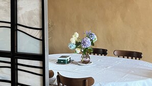 A dining area with a table set for two, a hanging light fixture, and a decorative vase with flowers. - The Touline Apple **** (Fécamp)