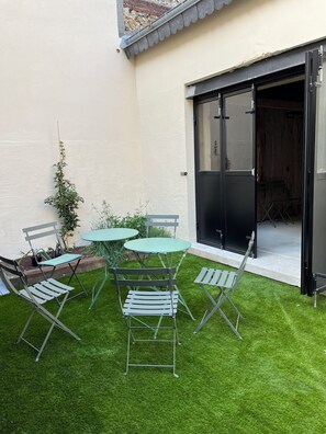 A small patio with a green lawn, a table, and four chairs. - The Touline Apple **** (Fécamp)