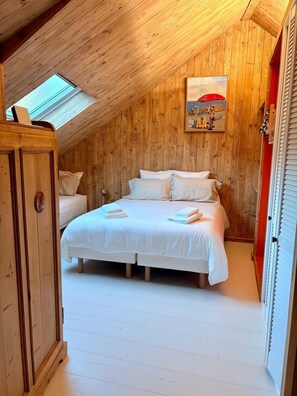 A bedroom with a sloped ceiling, wooden walls, a bed with white bedding, and a skylight. - The Touline Apple **** (Fécamp)