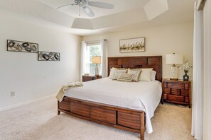 A bedroom with a large bed, wooden headboard, bedside tables, a ceiling fan, and artwork on the walls. - < 1 Mi to Brownwood Paddock Square: Home w/ Patio! (The Villages)