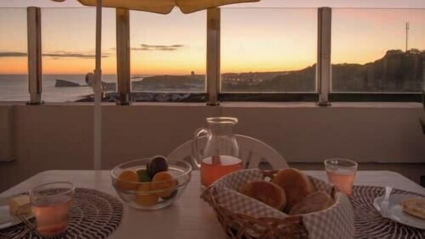 A table set for breakfast with a view of the sunset over the sea.