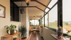 A corridor with a wooden floor, a sofa, and a window with a view of the countryside.
