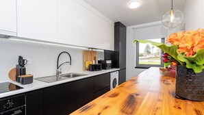 Une cuisine moderne dotée d’un plan de travail en bois, d’appareils électroménagers intégrés et offrant une vue sur l’extérieur.