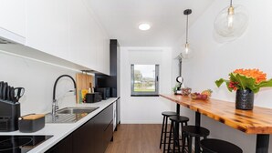 Une cuisine moderne avec un plan de travail en bois, des tabourets de bar noirs et une fenêtre donnant sur l’extérieur.