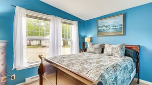 A bedroom with a bed, a dresser, a window with curtains, a painting on the wall, and a lamp on a nightstand. - 1 Mi to Beach: Cottage w/ Pool Access in Wells (Wells)