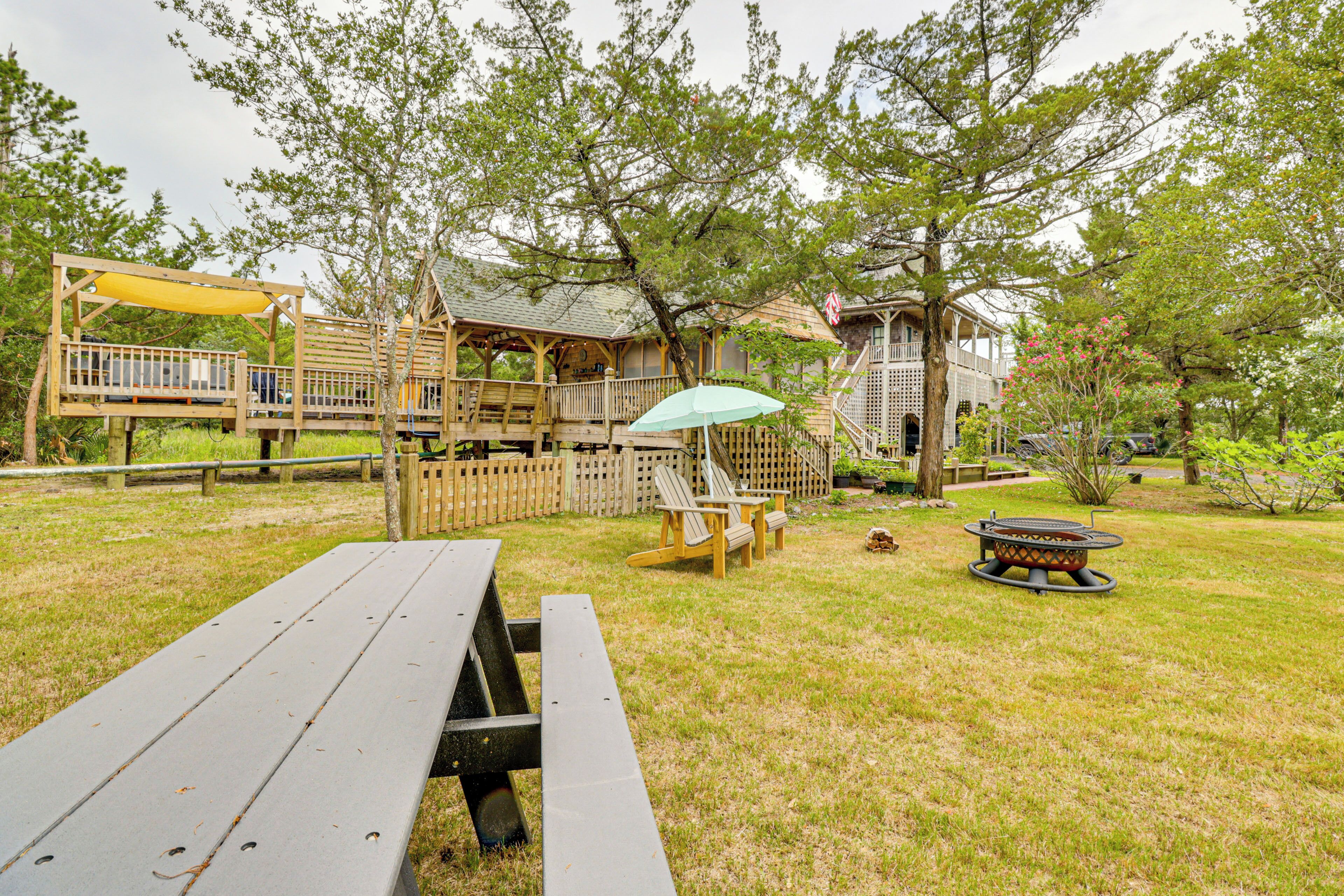 Eine Holzterrasse mit Picknicktisch, überdachter Sitzgelegenheit und Feuerstelle.