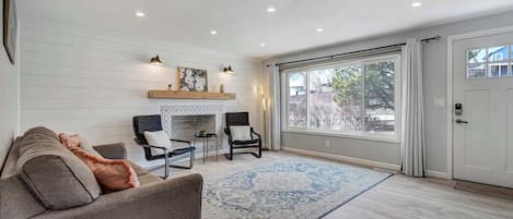 A spacious living room with a fireplace, a large window, and a sliding door.