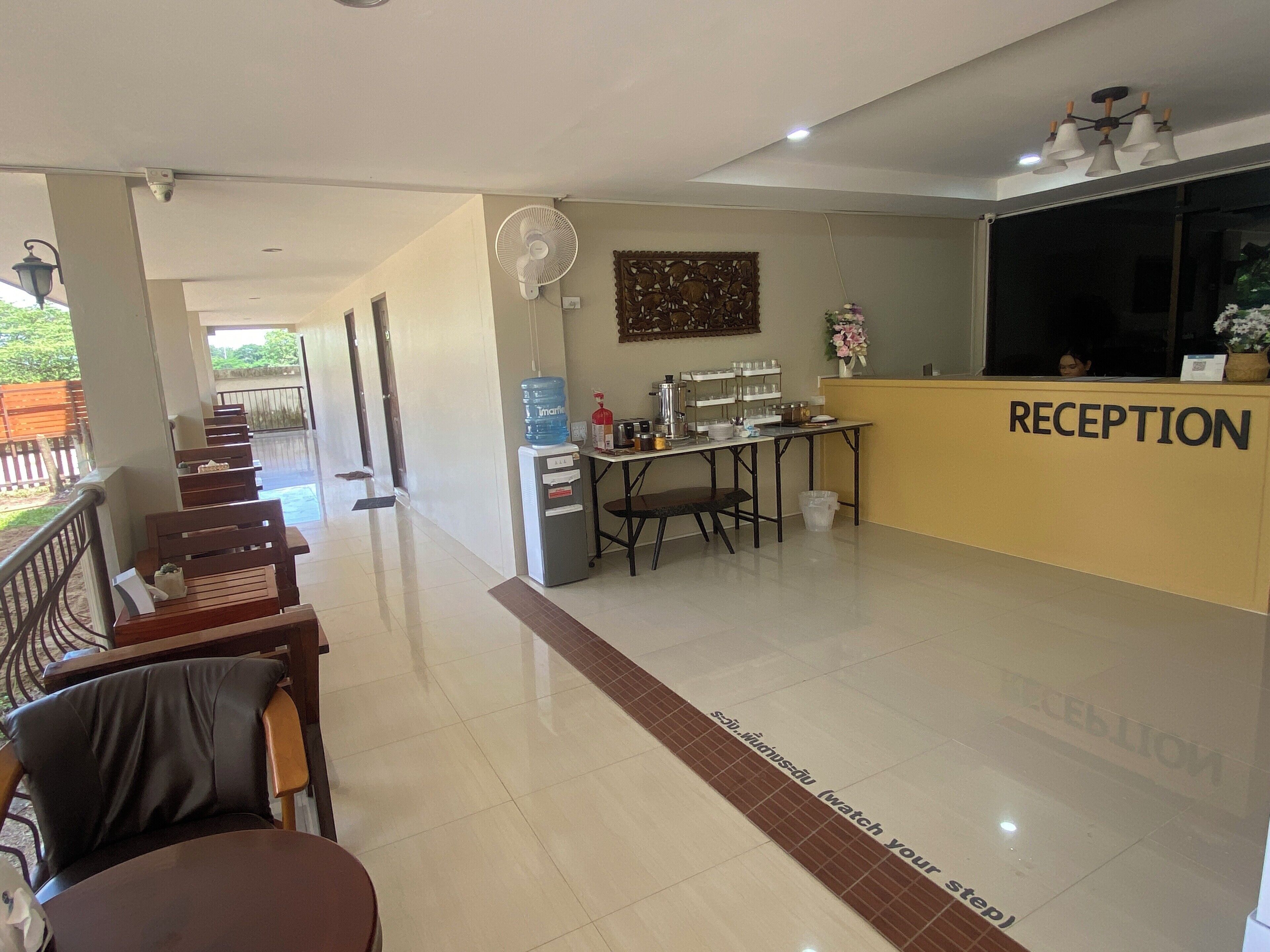 A reception area with a reception desk, chairs, a water dispenser, and a coffee machine.
