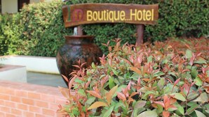 Une enseigne pour un hôtel-boutique, avec un chemin en briques et de la verdure à l’avant.