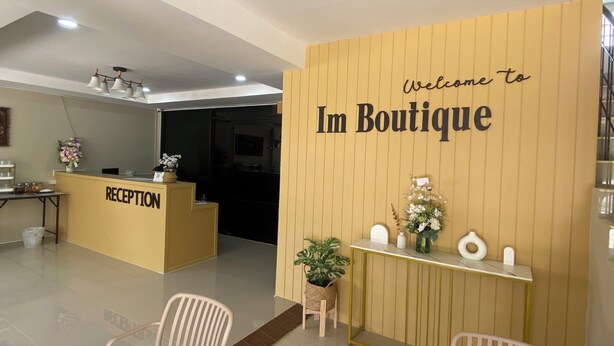 Un espace d’accueil avec un mur en bois sur lequel est inscrit « Bienvenue chez Im Boutique » et un comptoir d’accueil.