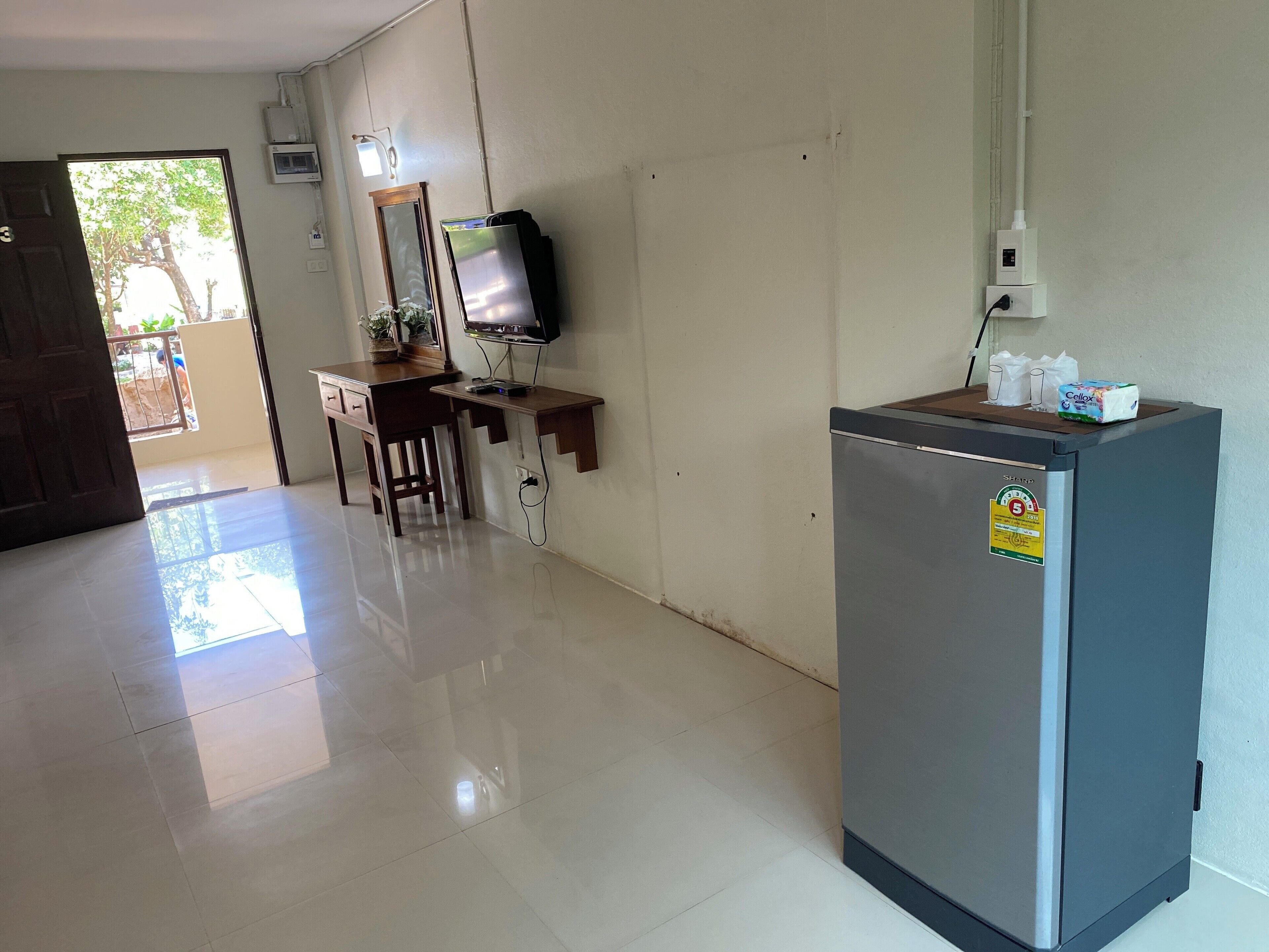 Una habitación con escritorio, silla y refrigerador.