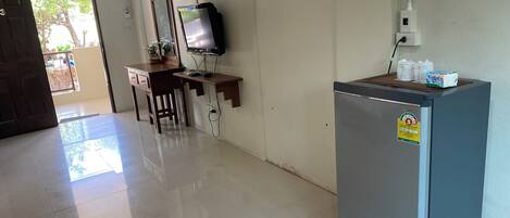 Una habitación con escritorio, silla y refrigerador.