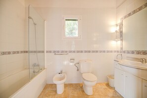 A bathroom with a glass-enclosed shower, a bidet, a toilet, and a sink.