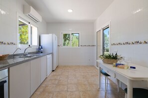 A modern kitchen with white cabinets, a granite countertop, a built-in dishwasher, and a window with a view of greenery.
