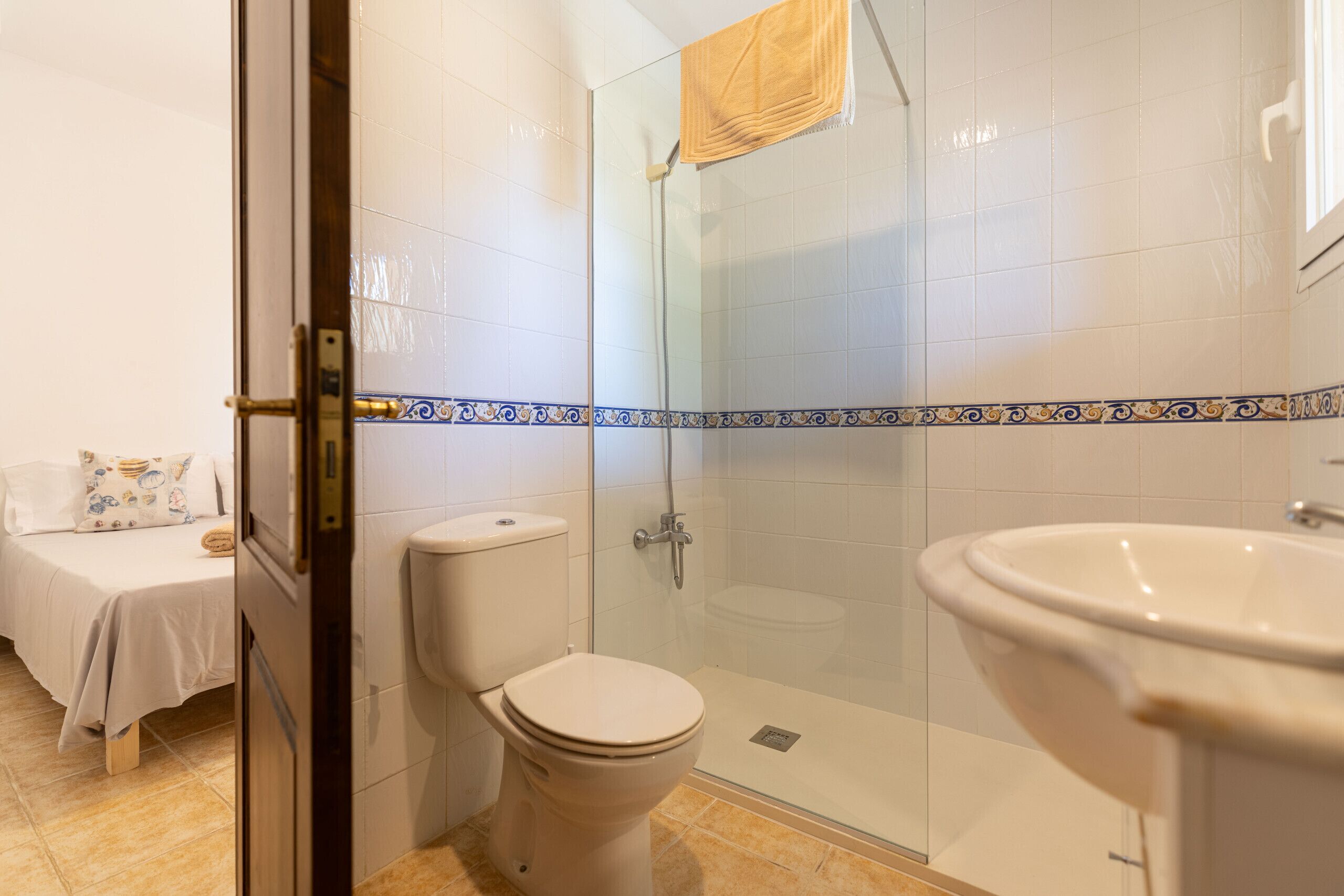 A bathroom with a glass-enclosed shower, a toilet, and a sink.