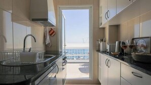 Uma cozinha moderna com vista para o mar, uma pia e um balcão com copos e uma torradeira.