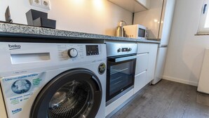A compact kitchen with a washing machine, oven, and microwave.