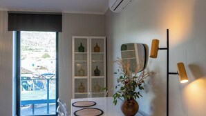 A modern room with a dining table, a vase with dried plants, a cabinet with glass doors, and a floor lamp.