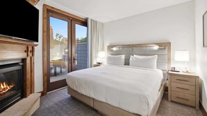 Ein Hotelzimmer mit einem großen Bett, einem Flachbildfernseher, einem Kamin und einem Balkon mit Aussicht.