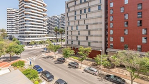 Une rue moderne en milieu urbain, bordée d’immeubles à plusieurs étages, dont un bâtiment à l’architecture originale, caractérisée par une forme incurvée, et une construction en briques rouges.