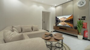 A modern living room with a sofa, a coffee table, and a flat-screen TV mounted on the wall.