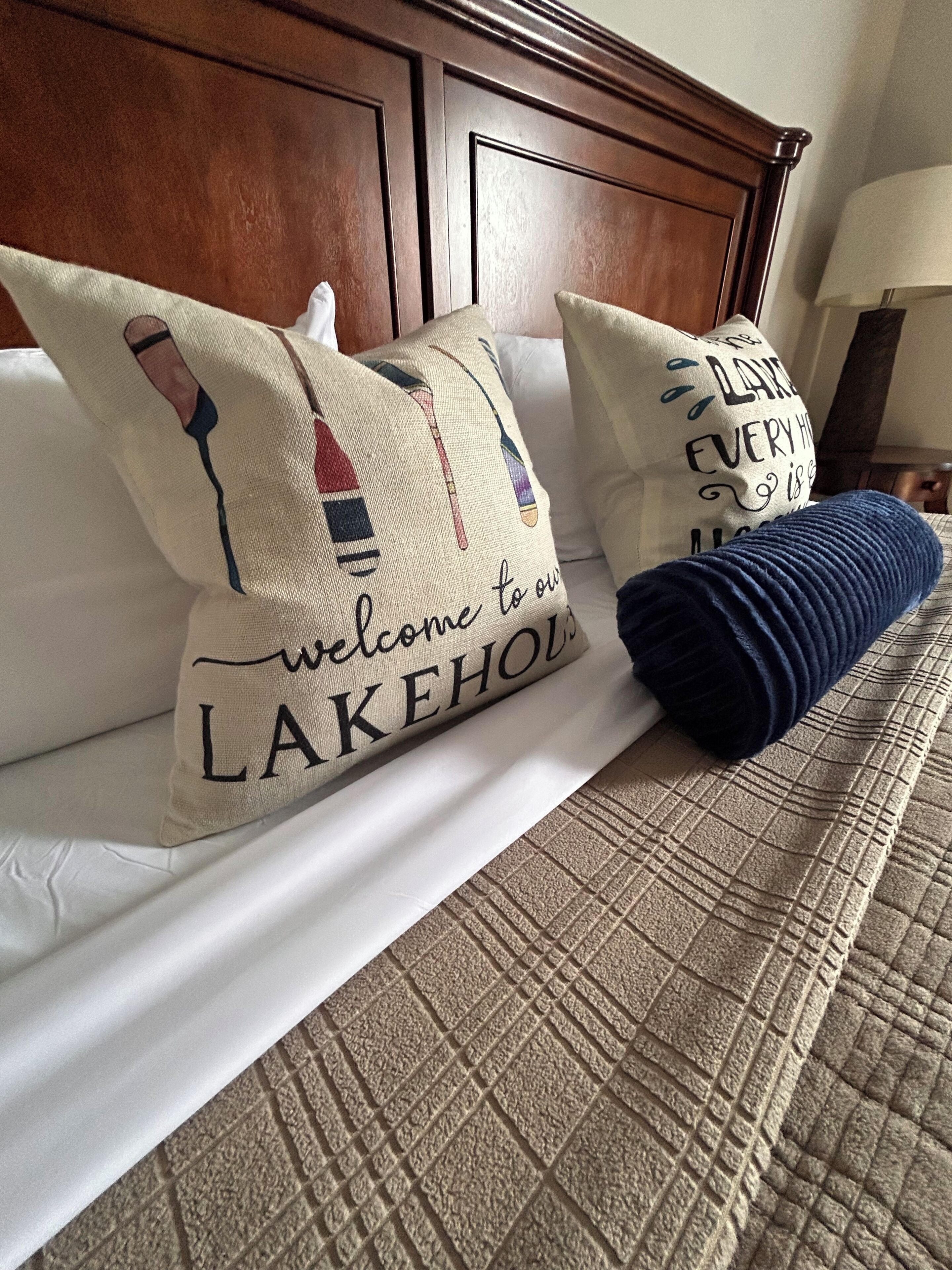 A bed with two pillows, one with a text design and the other with a blue pillow.
