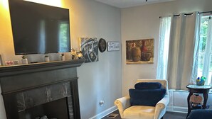 Ett vardagsrum med en öppen spis, en tv och en soffa.