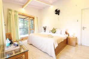 A bedroom with a bed, bedside table, lamp, and a window with curtains. - Hotel Green Oak (Nainital)