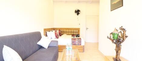 A living room with a sofa, a coffee table, and a bed with pillows.