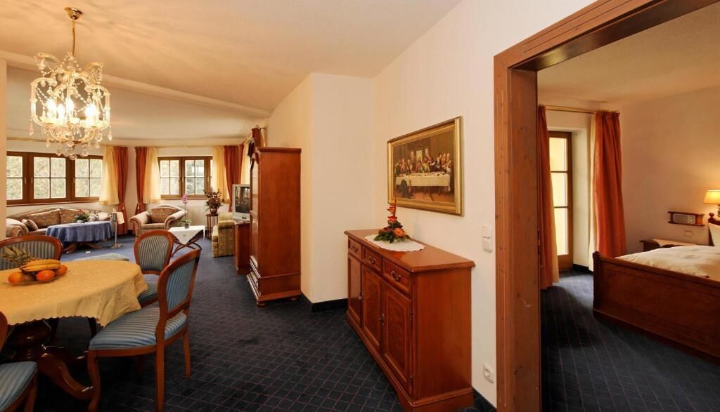 Habitación de hotel con comedor, una cama, un armario de madera y un cuadro en la pared.