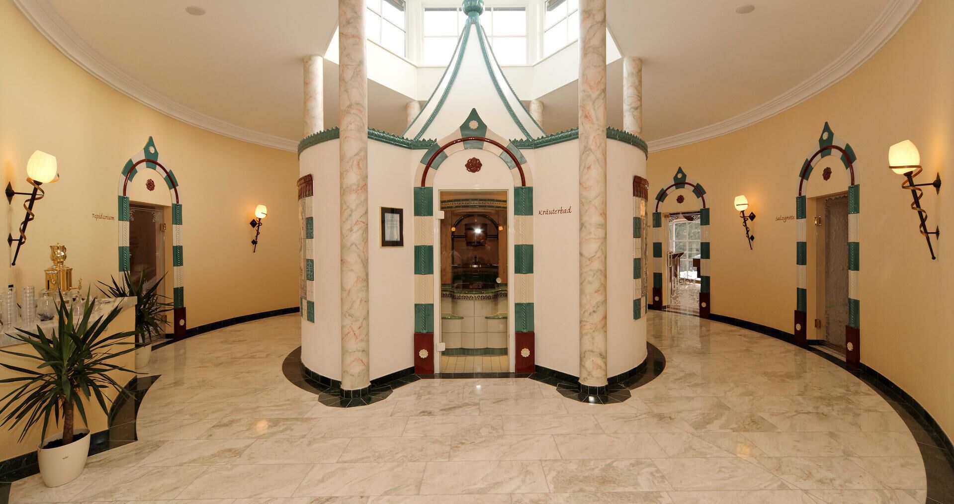 Un vaste hall d’entrée avec un sol en marbre, une arche centrale et des colonnes décoratives.